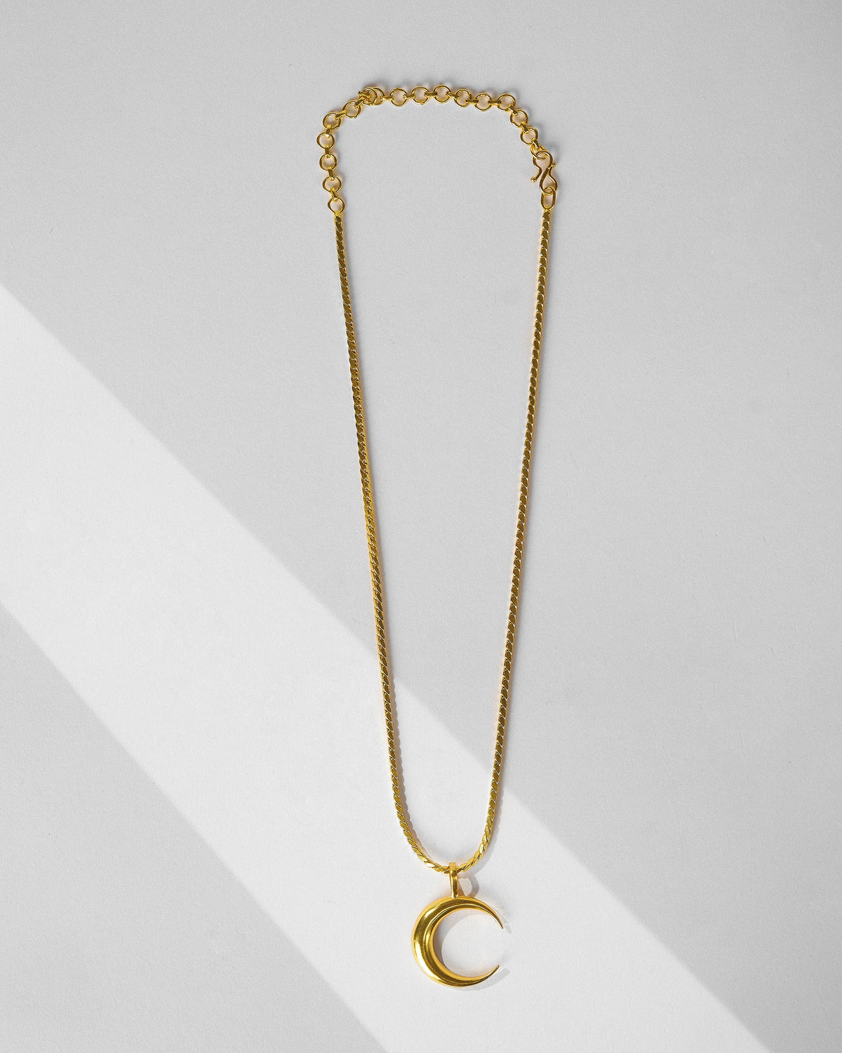 Gold Moonfall necklace with a crescent pendant laid flat.