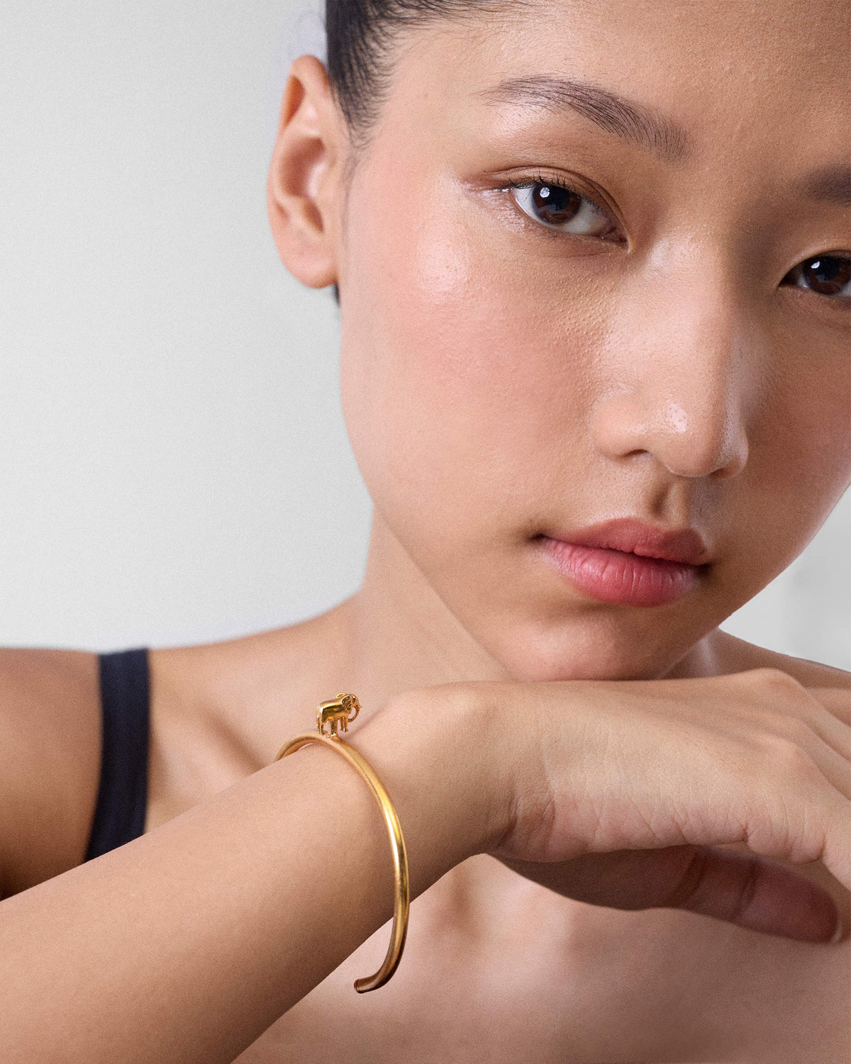 Person wearing a slim gold haathi cuff with an elephant charm.