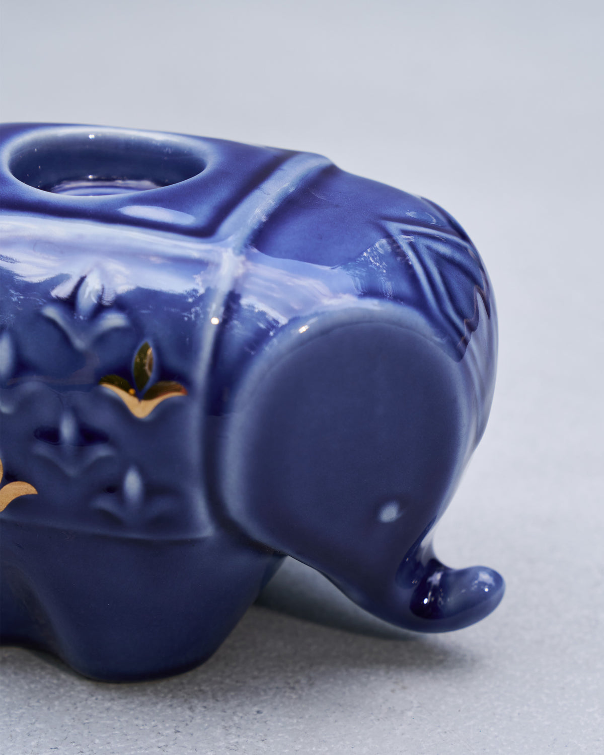Close-up of a blue Tusker votive showing gold embossing and the tealight well.