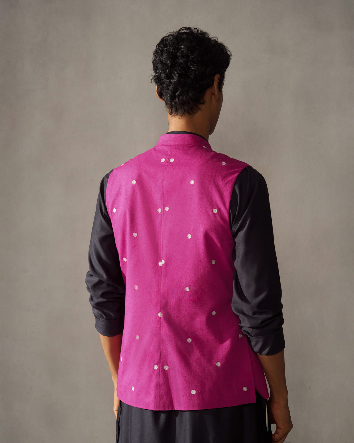 Back of a magenta Nehru jacket with silver embroidery worn by a person.