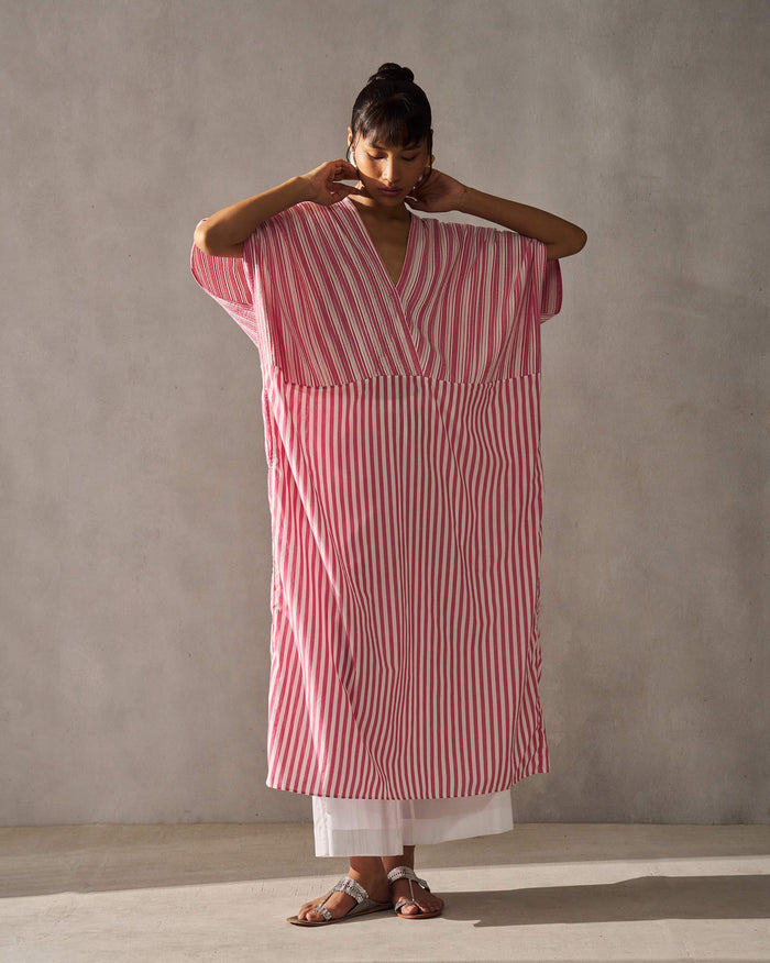Person wearing a Sarai Kaftan in fuchsia and ivory stripes with dropped sleeves.