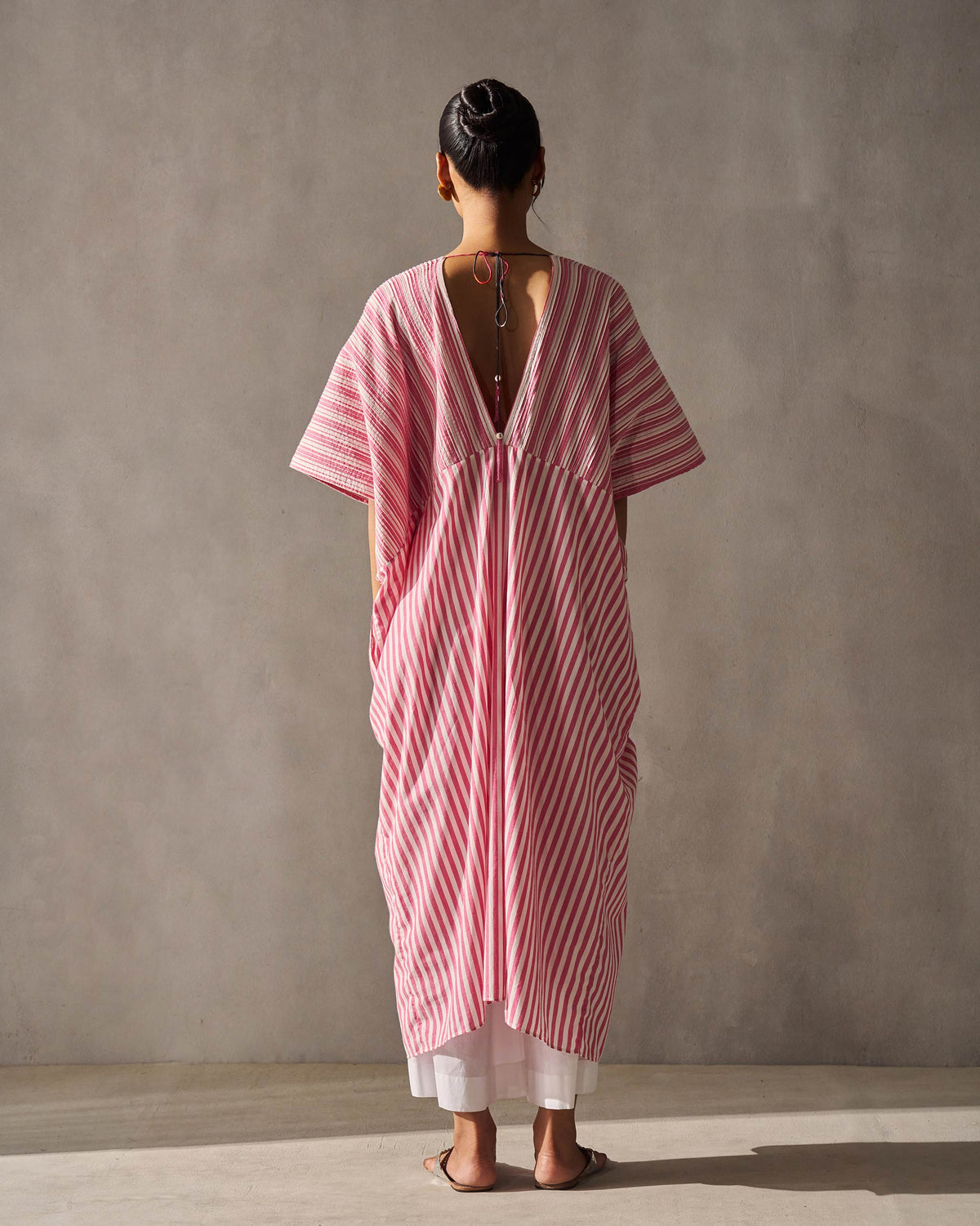 Back of a Sarai Kaftan worn by a person, showing its striped draped silhouette.