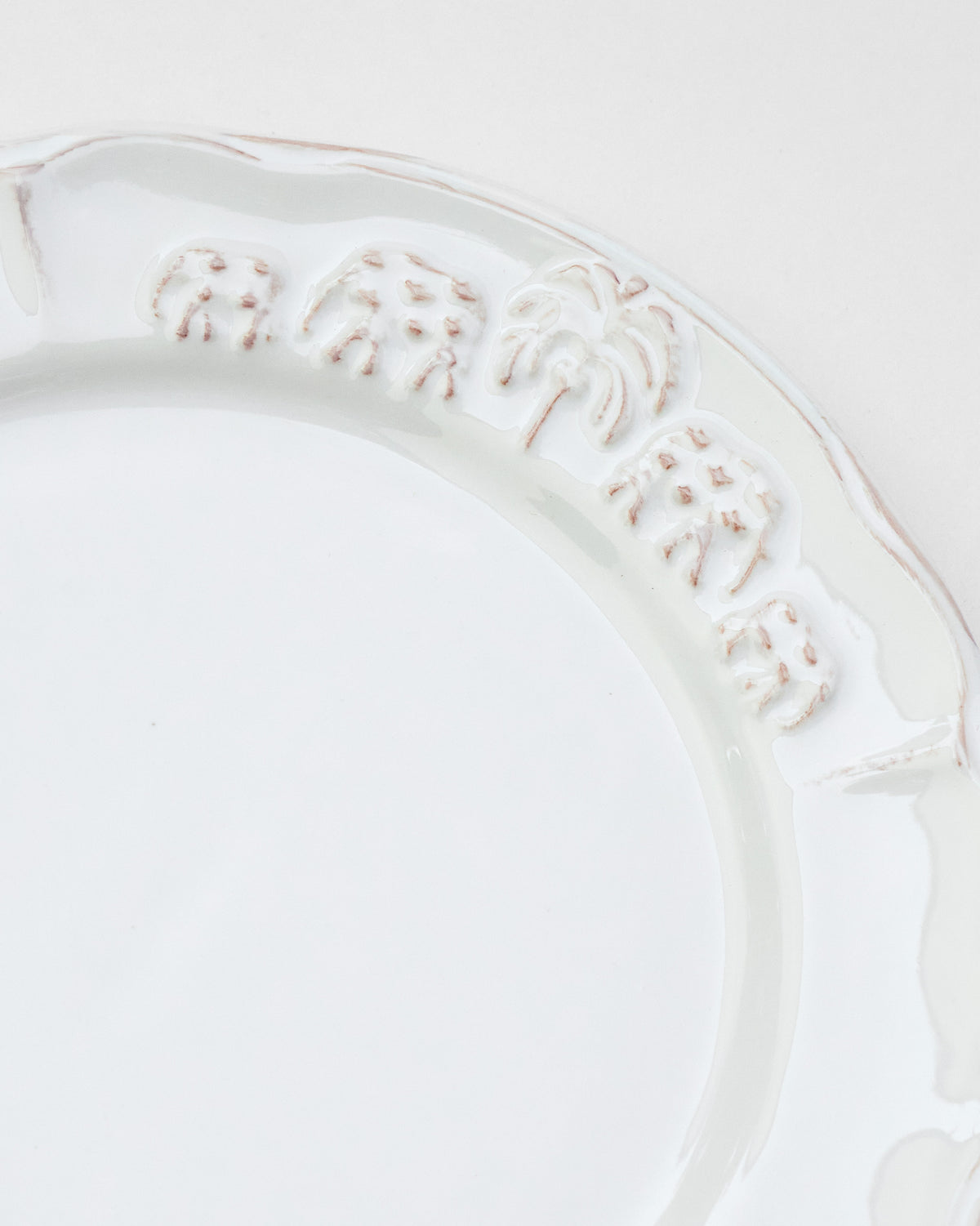 Close-up of Ele Palm plate rim with embossed elephants and palm.