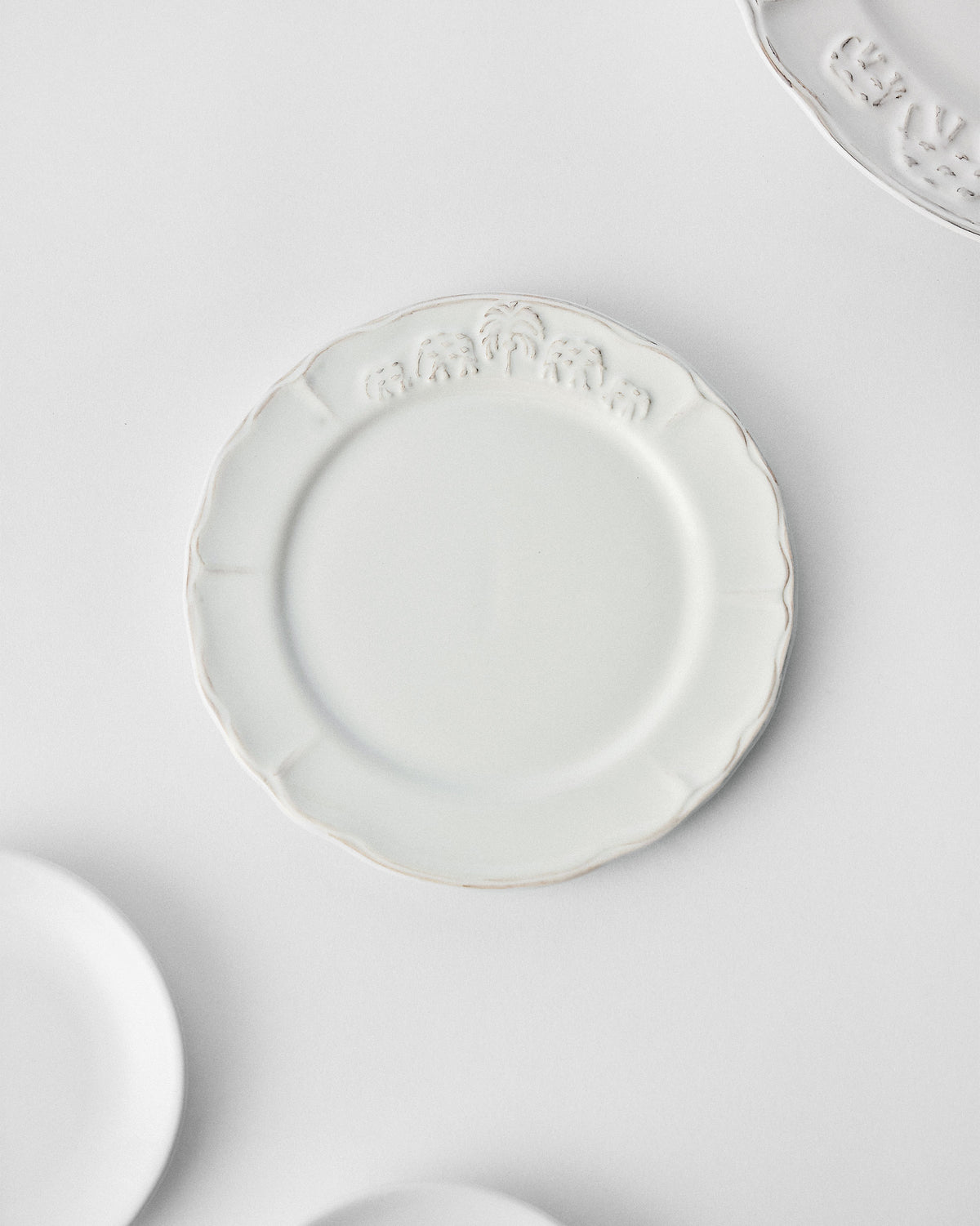 Overhead view of a white Ele Palm quarter plate with elephant relief.