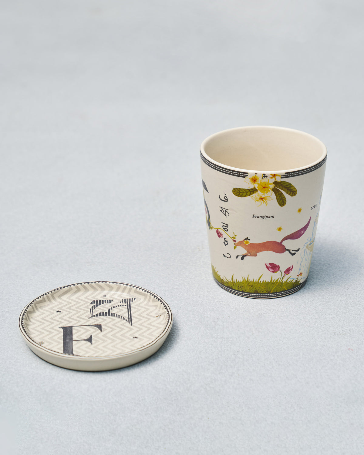 F Alphabet mug with fox and frangipani motifs beside a letter F coaster.