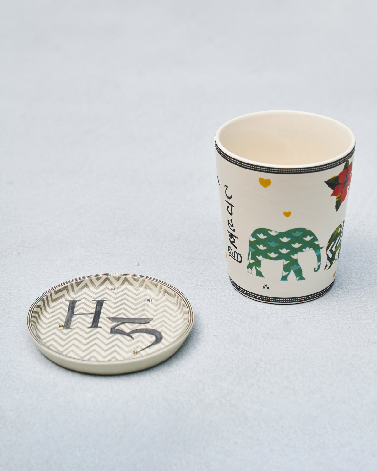 H Alphabet cup with elephant and hibiscus motifs beside a letter H coaster.