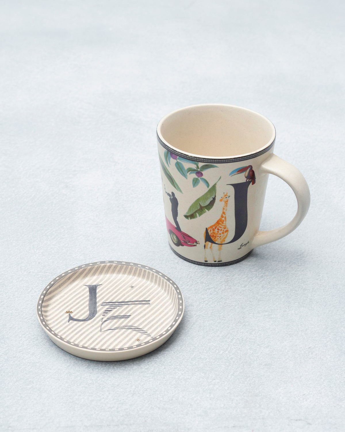 J Alphabet mug with giraffe and jungle motifs beside a matching coaster.