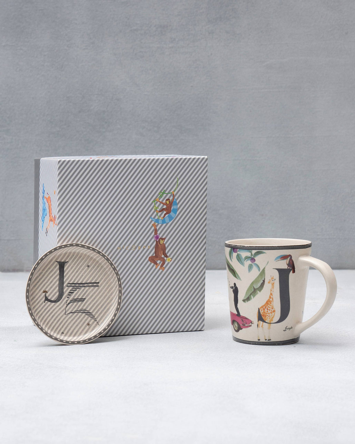 J Alphabet mug and coaster with letter J motifs beside a striped Nicobar gift box.