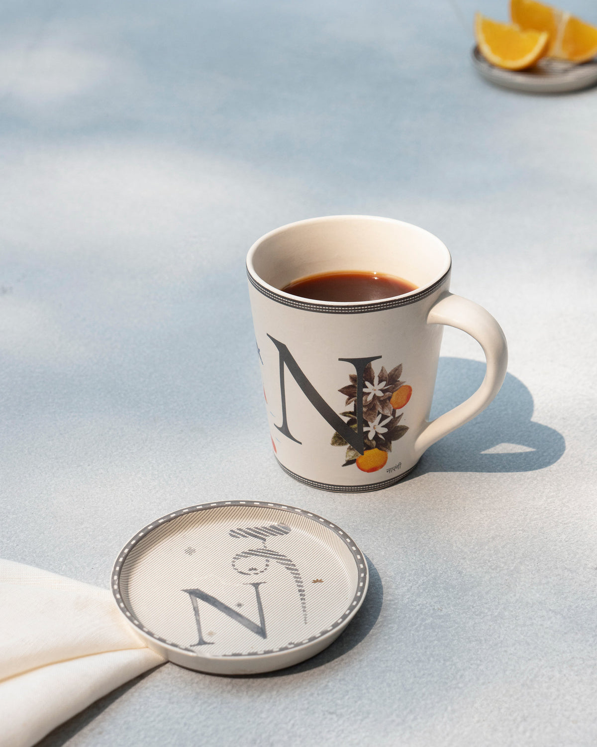 N alphabet mug filled with coffee beside a matching N coaster.