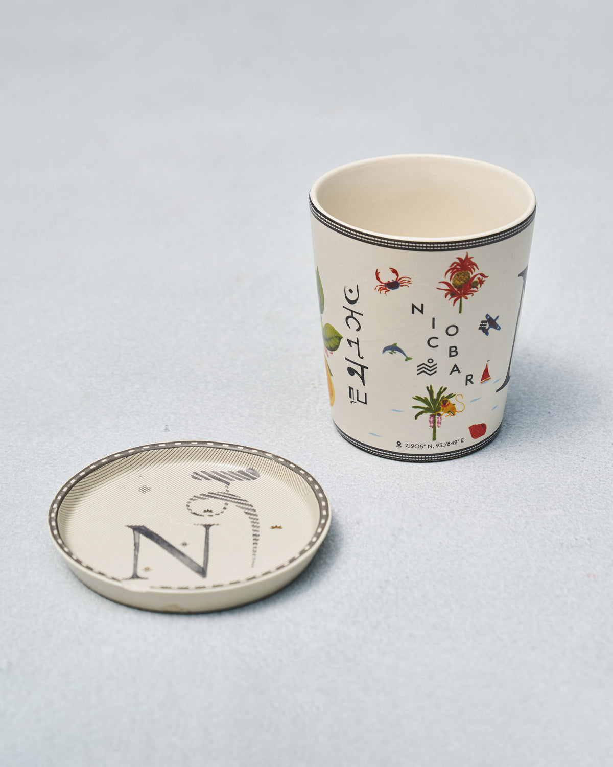 N alphabet set cup with travel icons beside a coaster marked with the letter N.