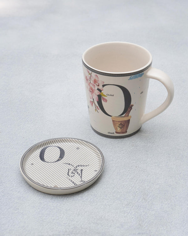 The O mug with orchids beside its coaster
