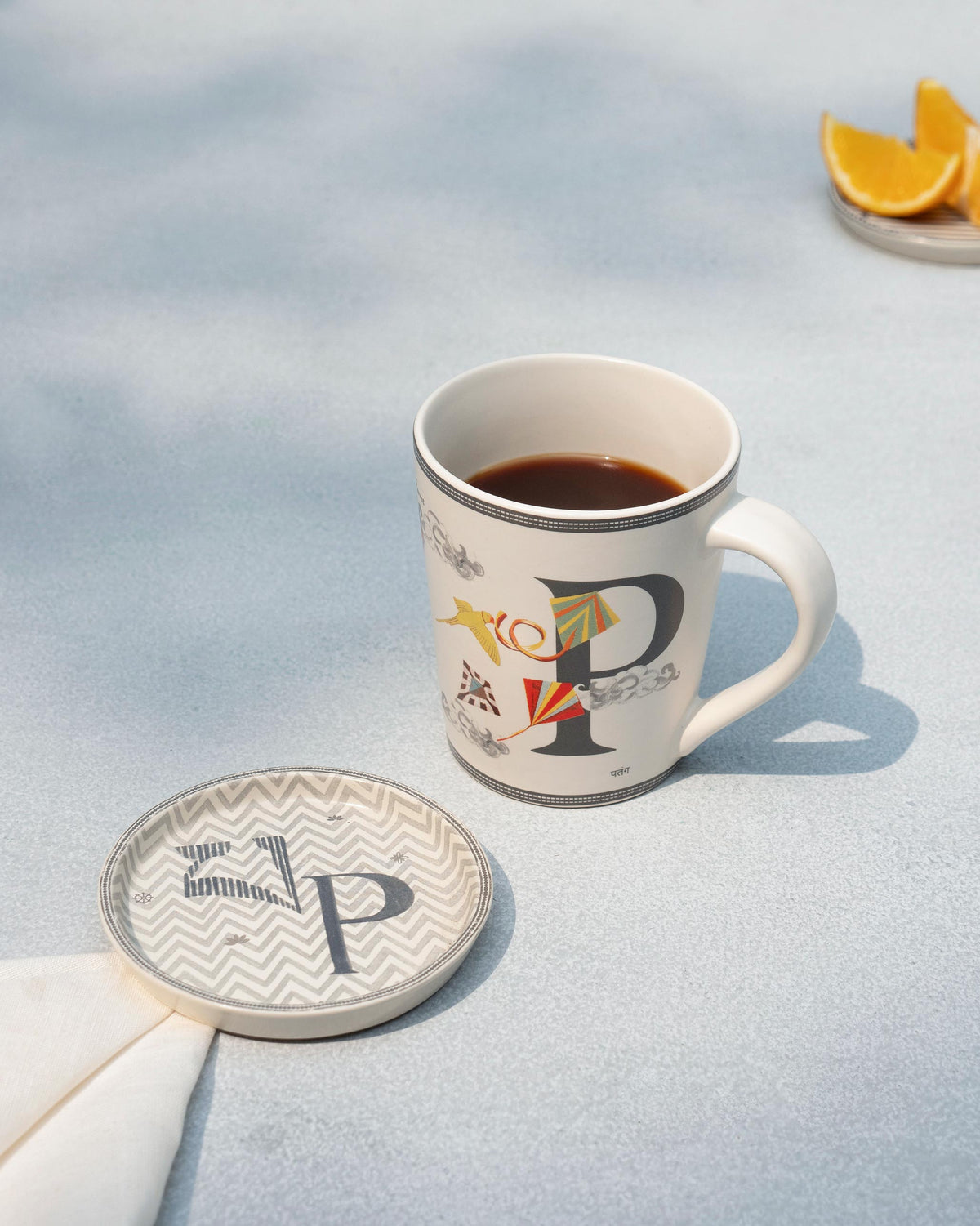 P alphabet mug filled with coffee beside a matching P coaster.
