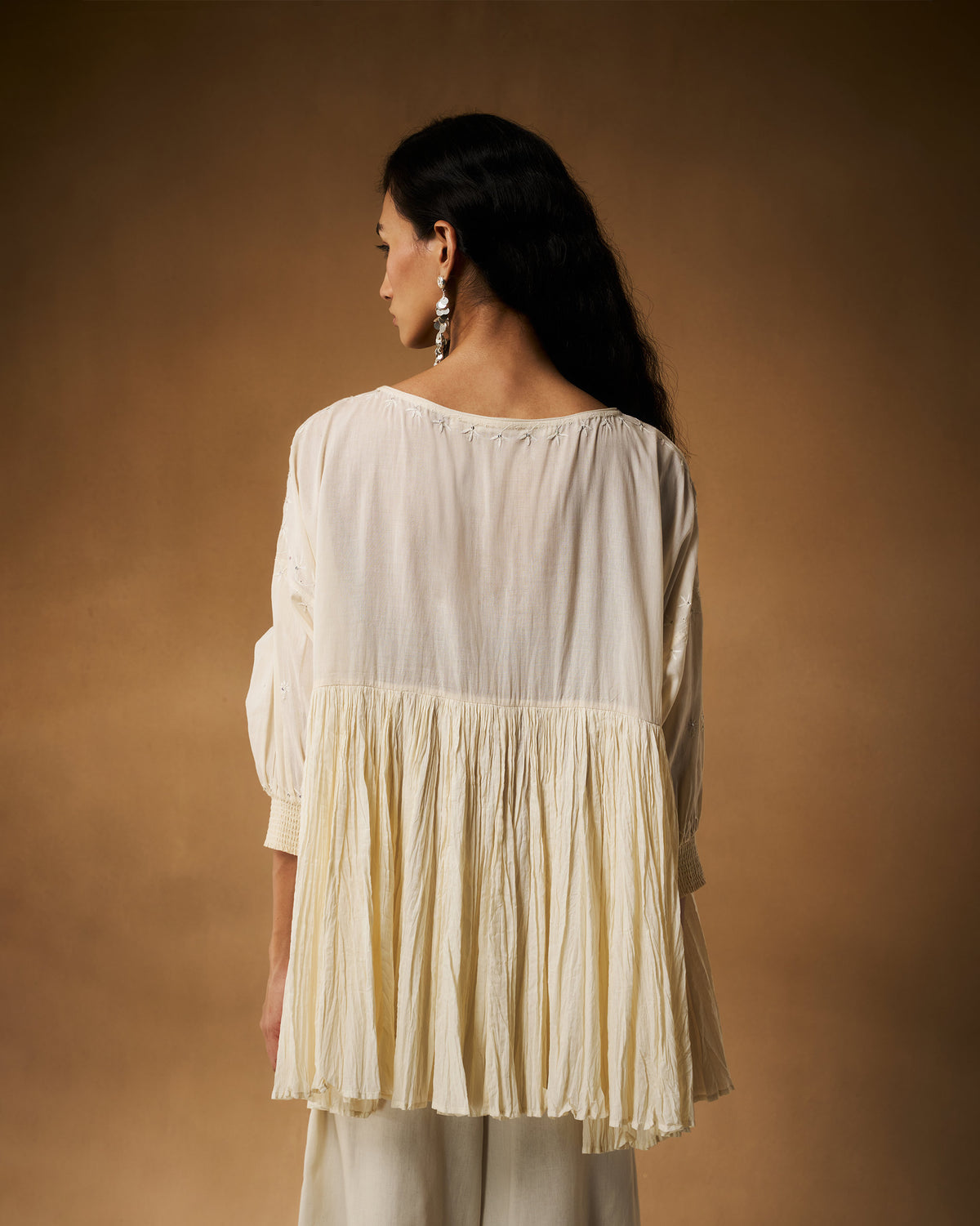 Back of an ivory chikankari Taabir top with a gathered pleated peplum.