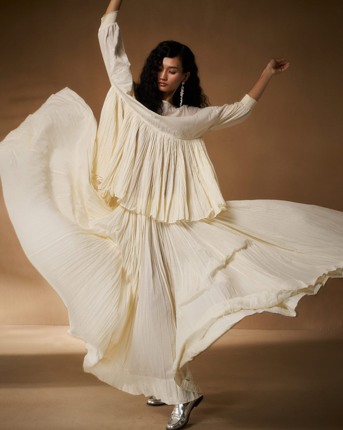 Person wearing an ivory chikankari Taabir top with voluminous pleats in motion.