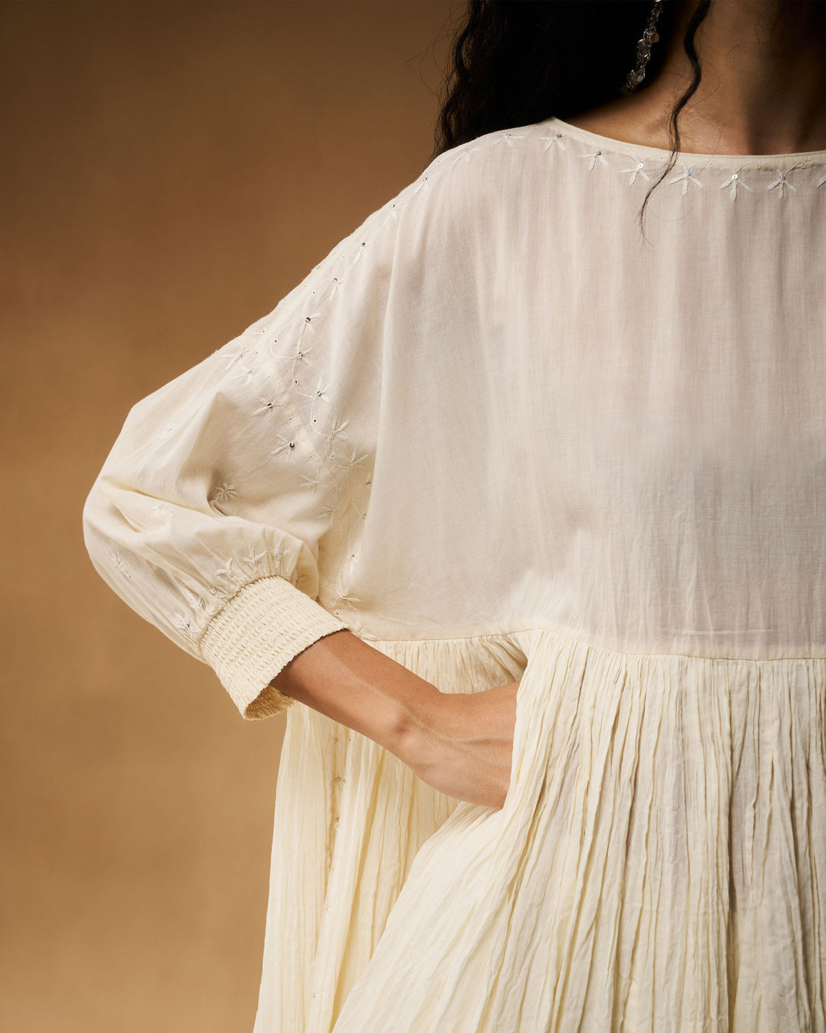 Side view of an ivory chikankari Taabir top showing a side pocket and smocked cuff.