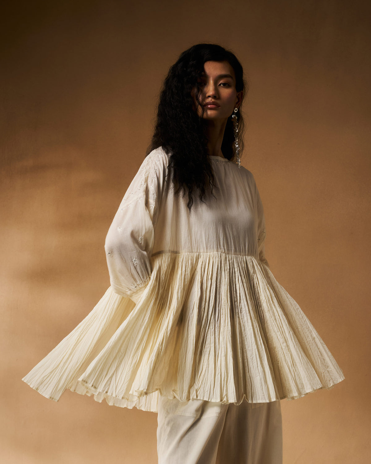 Person wearing an ivory chikankari Taabir top with a wide pleated peplum.