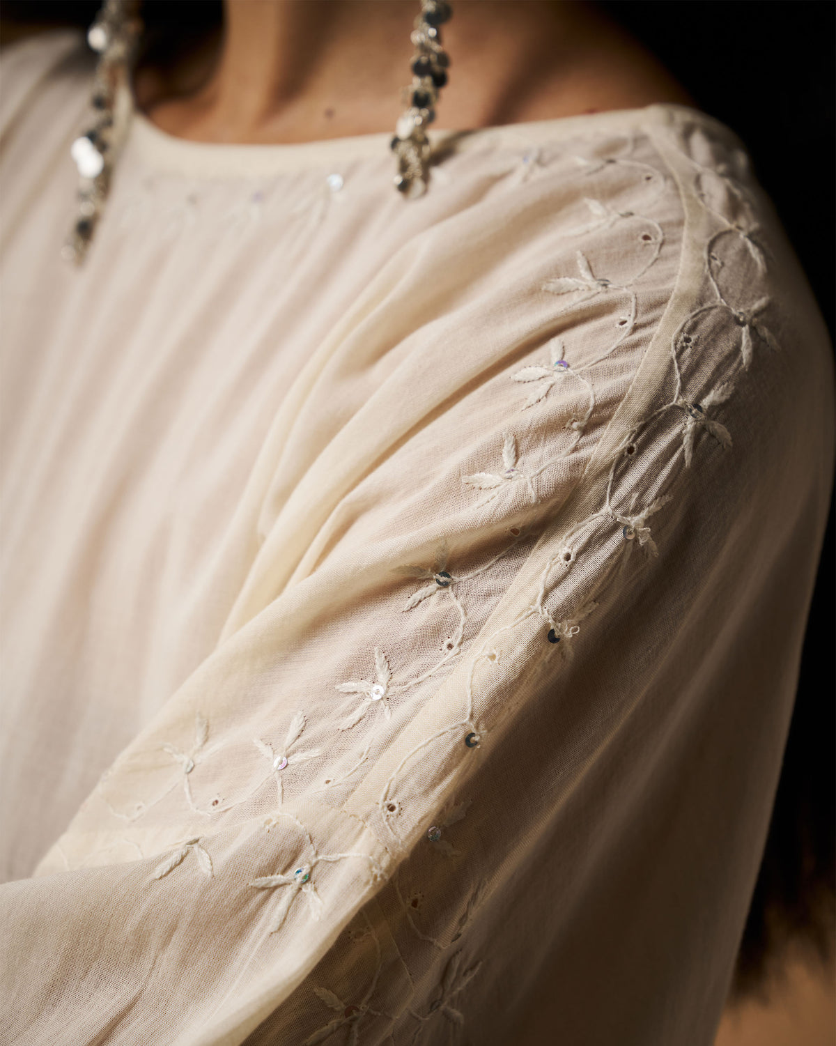 Close-up of floral chikankari embroidery on the shoulder of an ivory Taabir top.