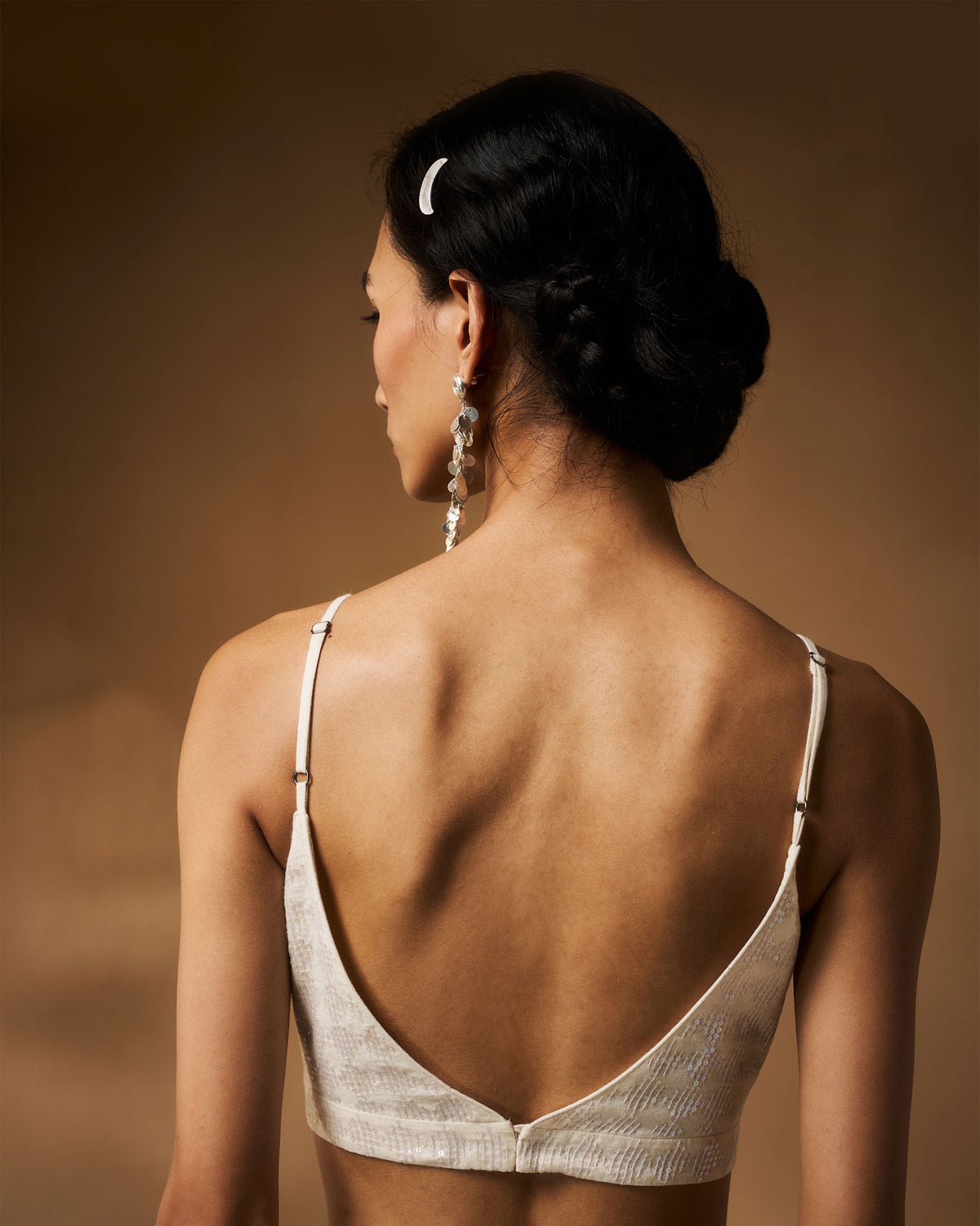 Back of an ivory sequined strappy blouse with a deep V opening.