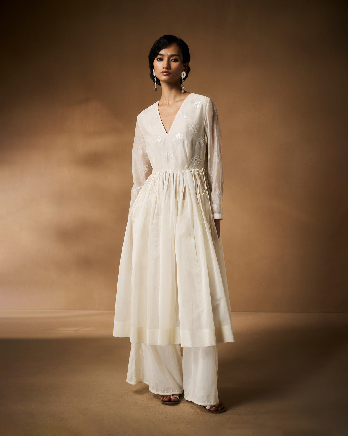 Person wearing an ivory Amaya kurta with tonal floral embroidery and a gathered waist.
