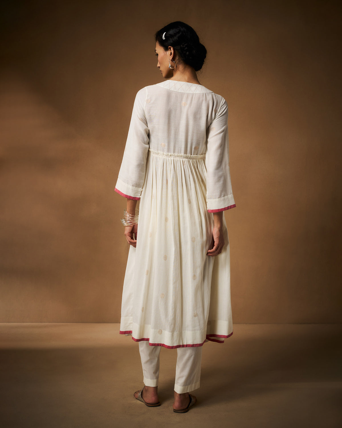 Back of a gathered ivory Sukoon angrakha with pink hem trim.