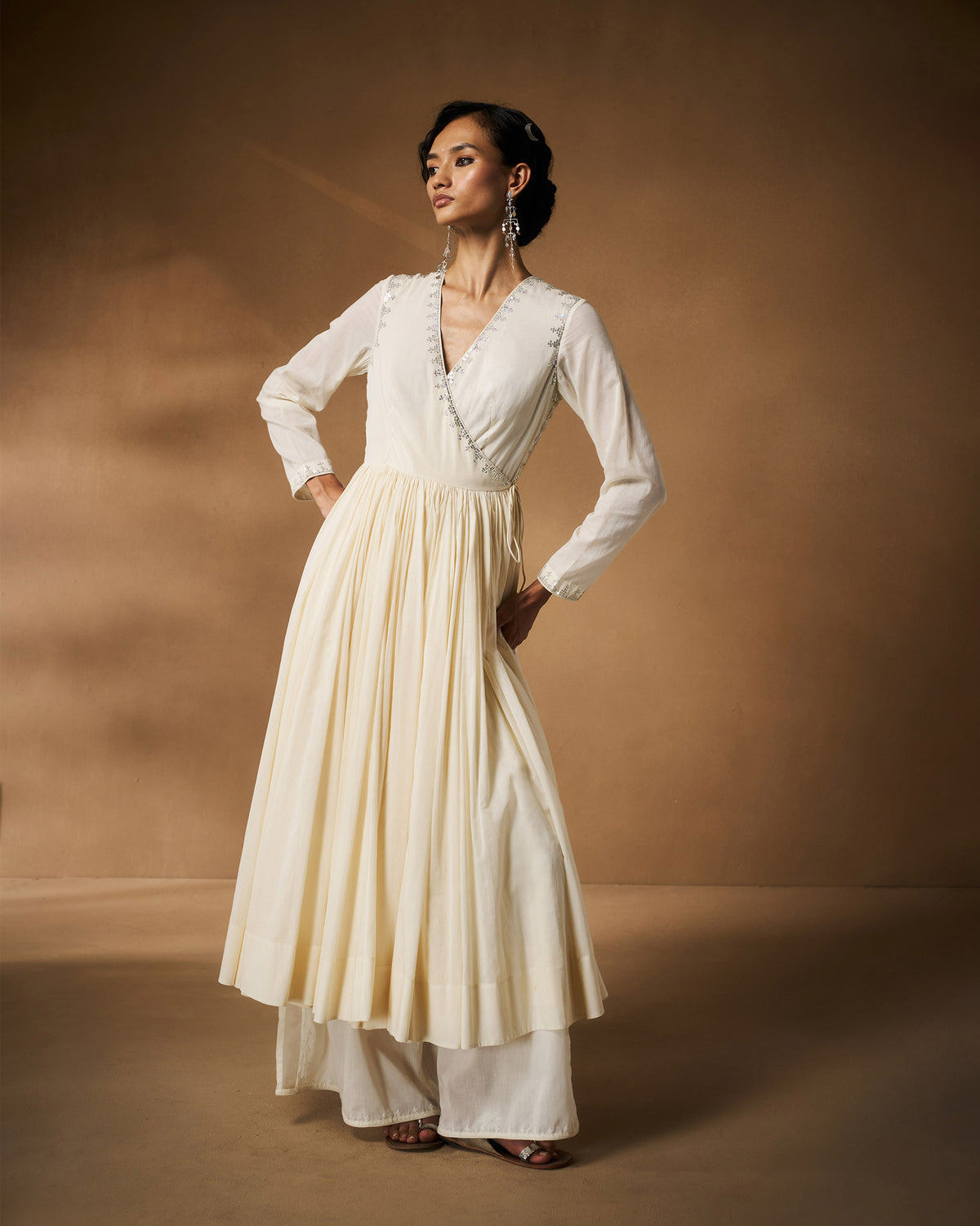 Person wearing an ivory Aafreen Angrakha with silver embroidered neckline.