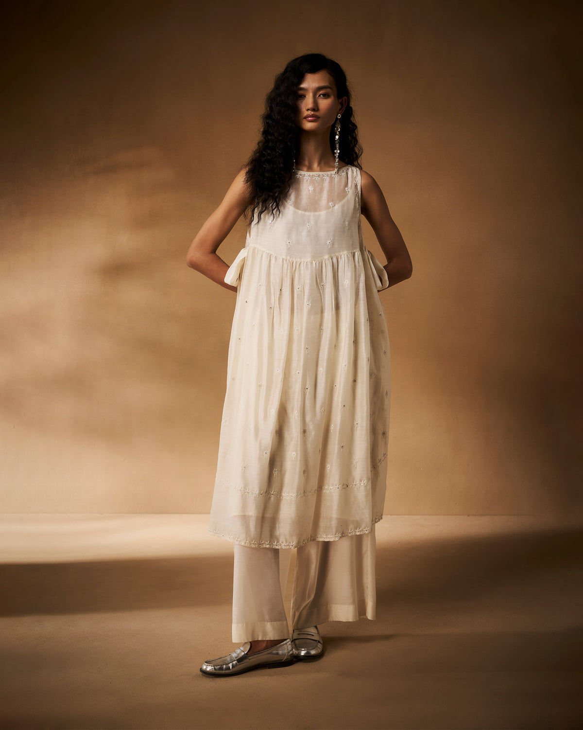 Person wearing an ivory chikankari Afra tunic with side ties over wide trousers.