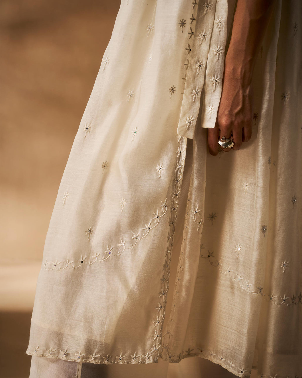 Close-up of ivory chikankari embroidery along the Afra tunic side slit and hem.