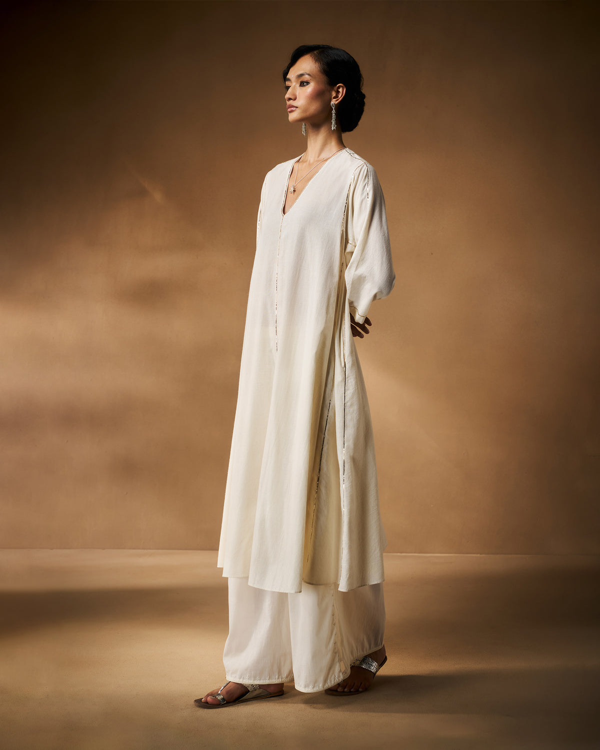 Side view of an ivory Aheli Kurta with silver trim along the side slits.