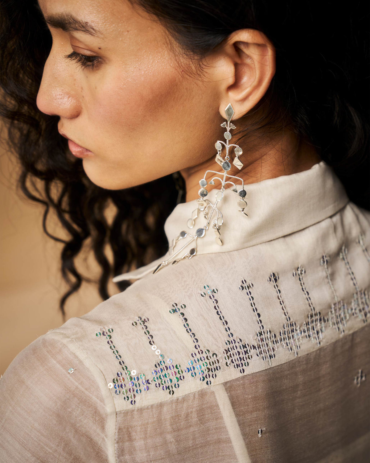 Close-up of sequin embroidery on the shoulder of an ivory Qurbat dress.