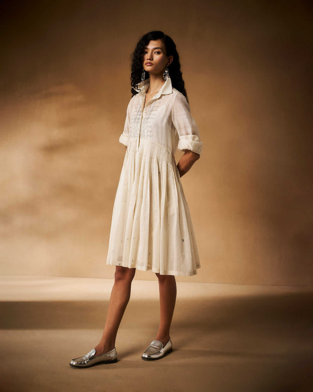 Person wearing an ivory Qurbat dress with silver accents.