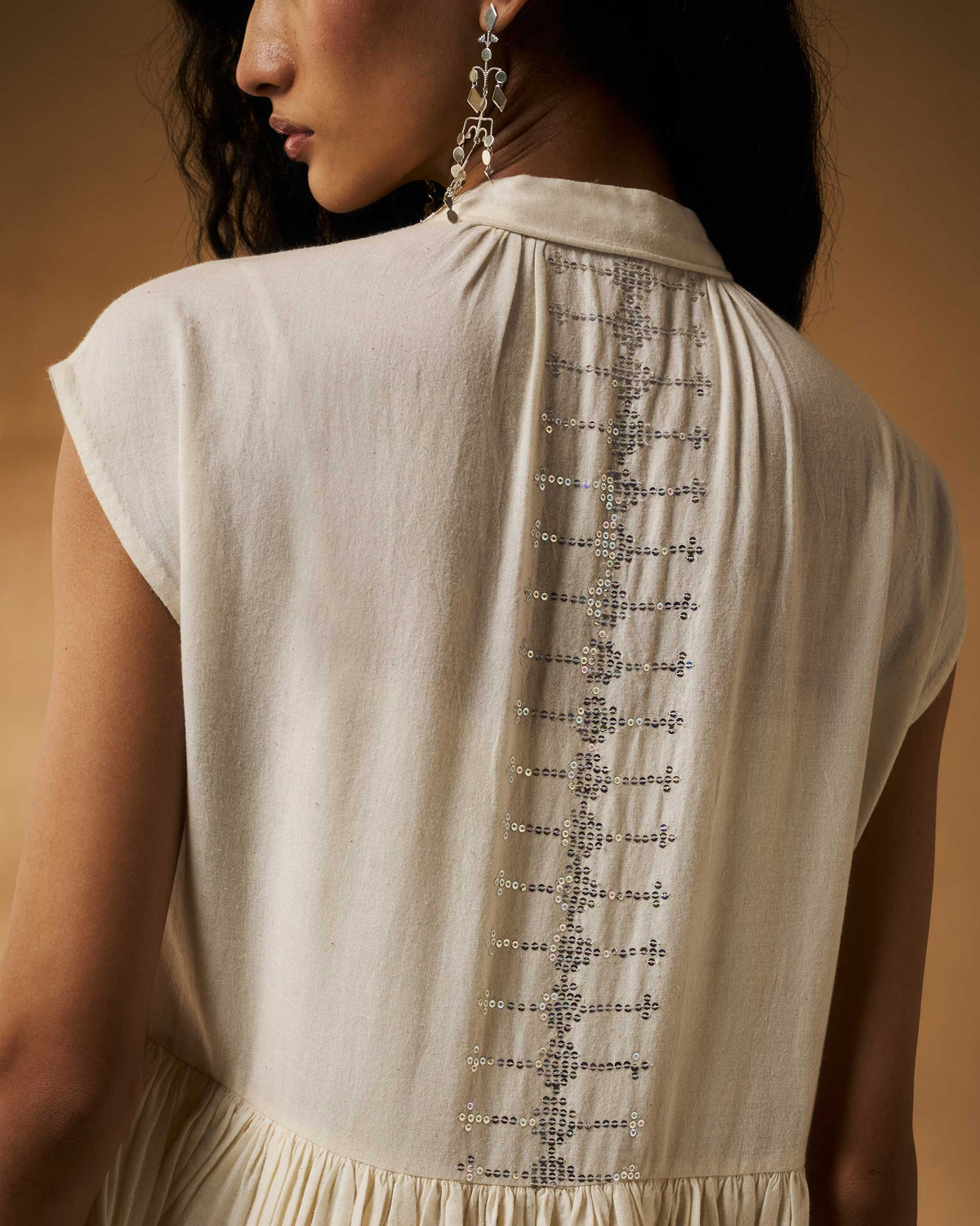 Close-up of silver sequin embroidery down the back of an ivory Mina Dress.