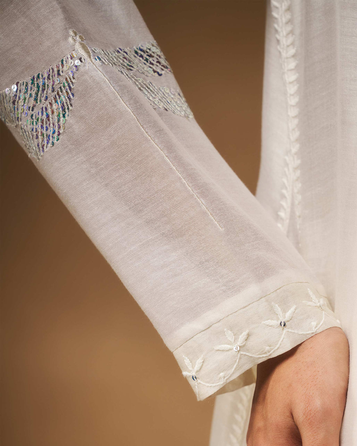 Close-up of silver sequin motifs on an ivory Pavi overlay sleeve.