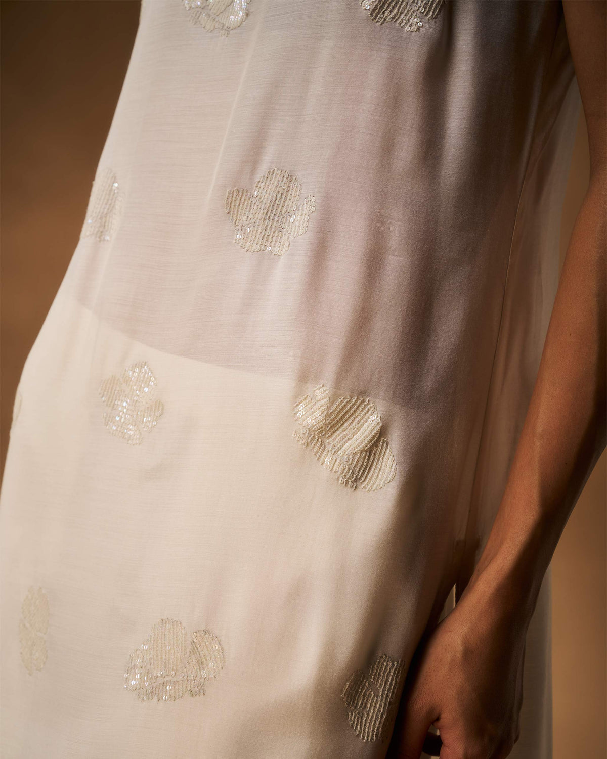 Close-up of an ivory camisole with tonal sequinned flower embroidery.