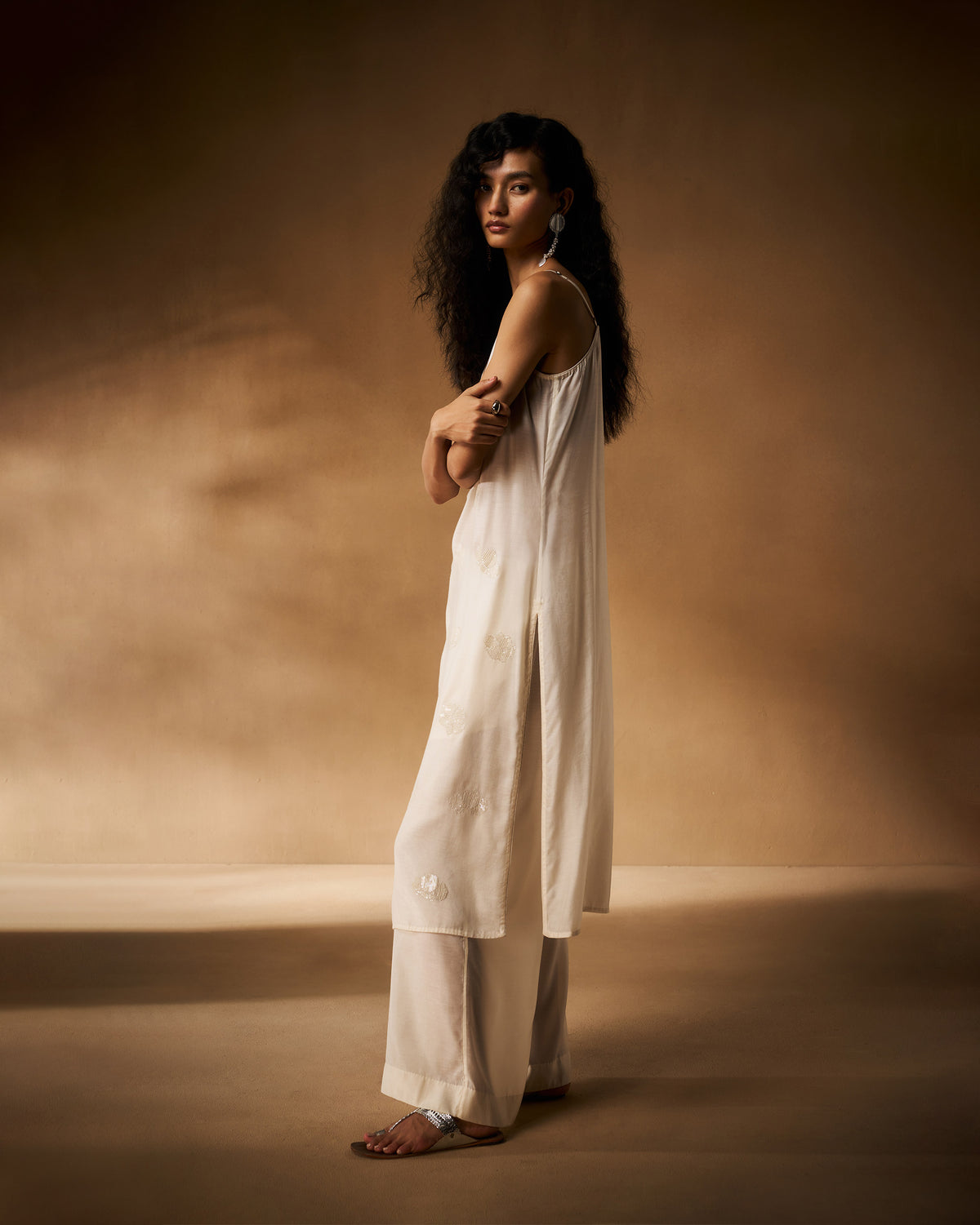 Side view of a long ivory embroidered camisole with side slits.
