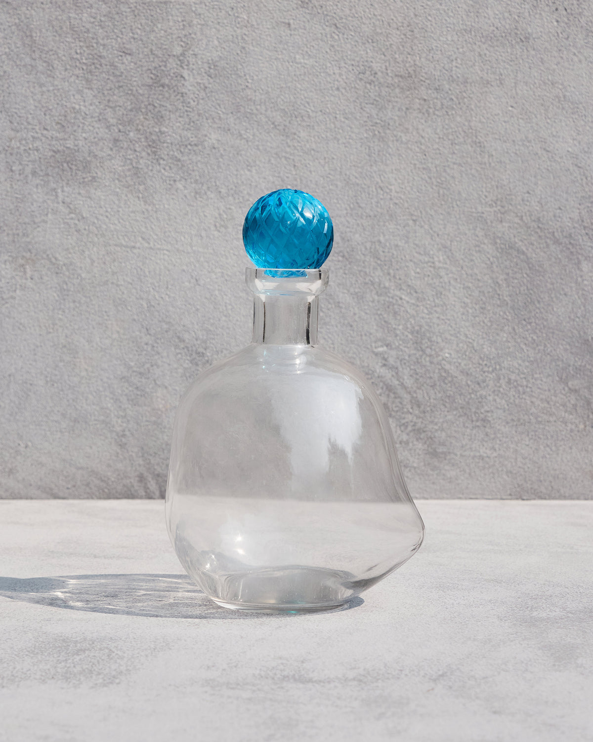 Clear glass Revel Decanters with a faceted blue stopper.