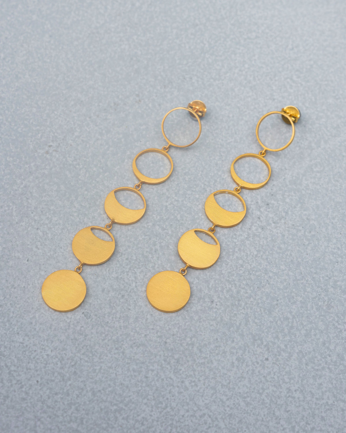 Pair of gold Waxing Moon danglers with linked moon-phase circles laid flat.