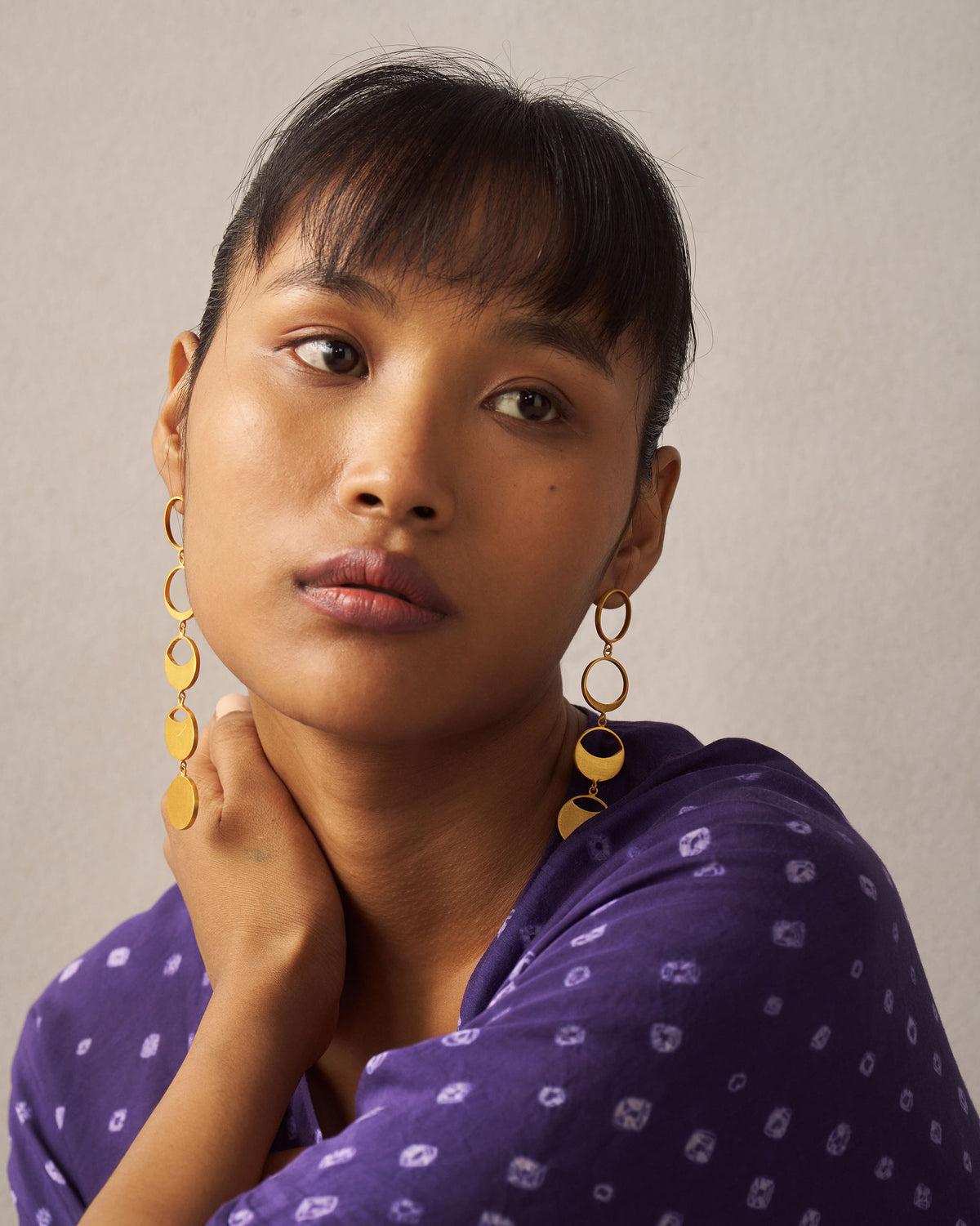 Person wearing long gold Waxing Moon danglers with moon-phase drops.