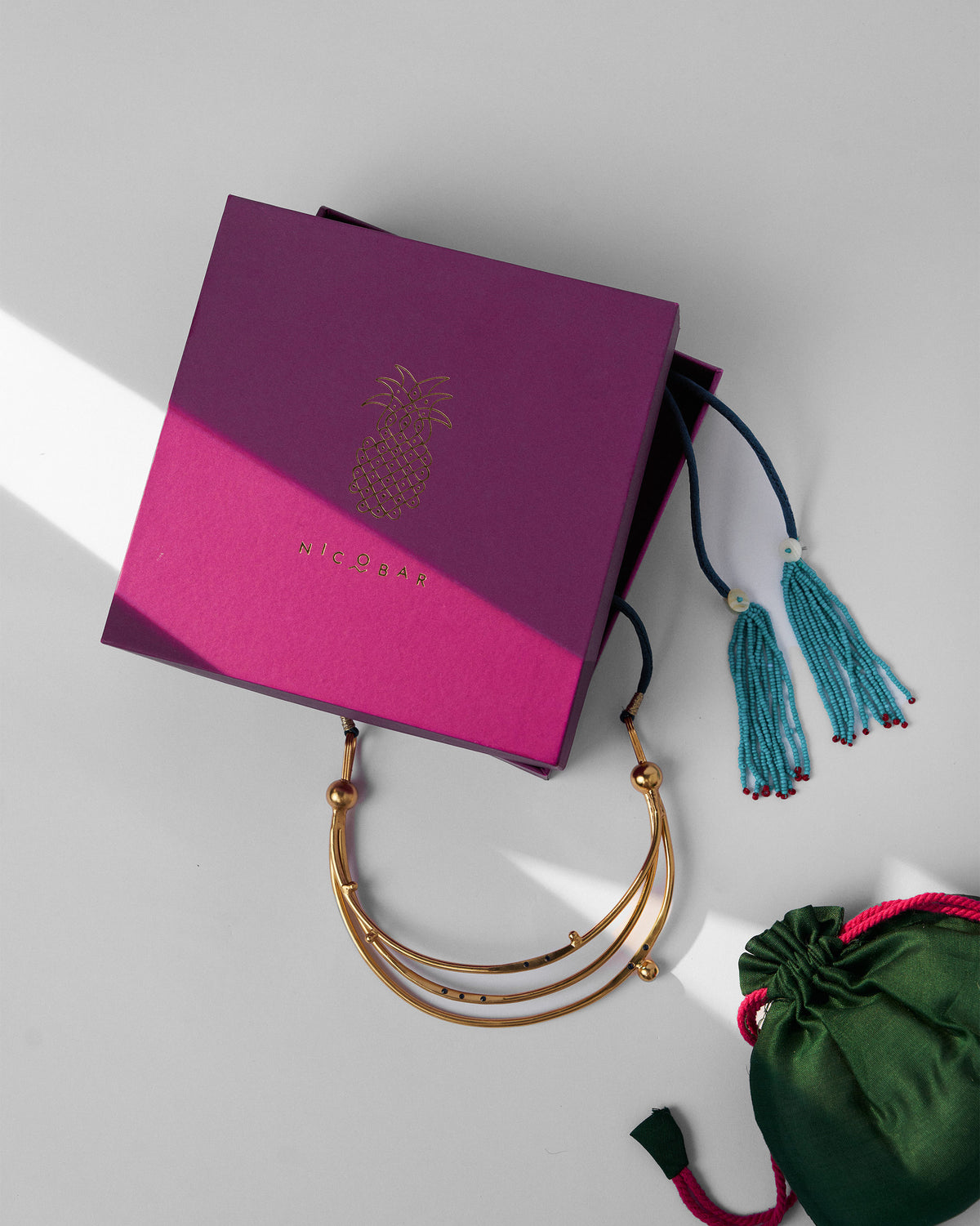 Gold Celestial choker with a magenta Nicobar gift box and green pouch.
