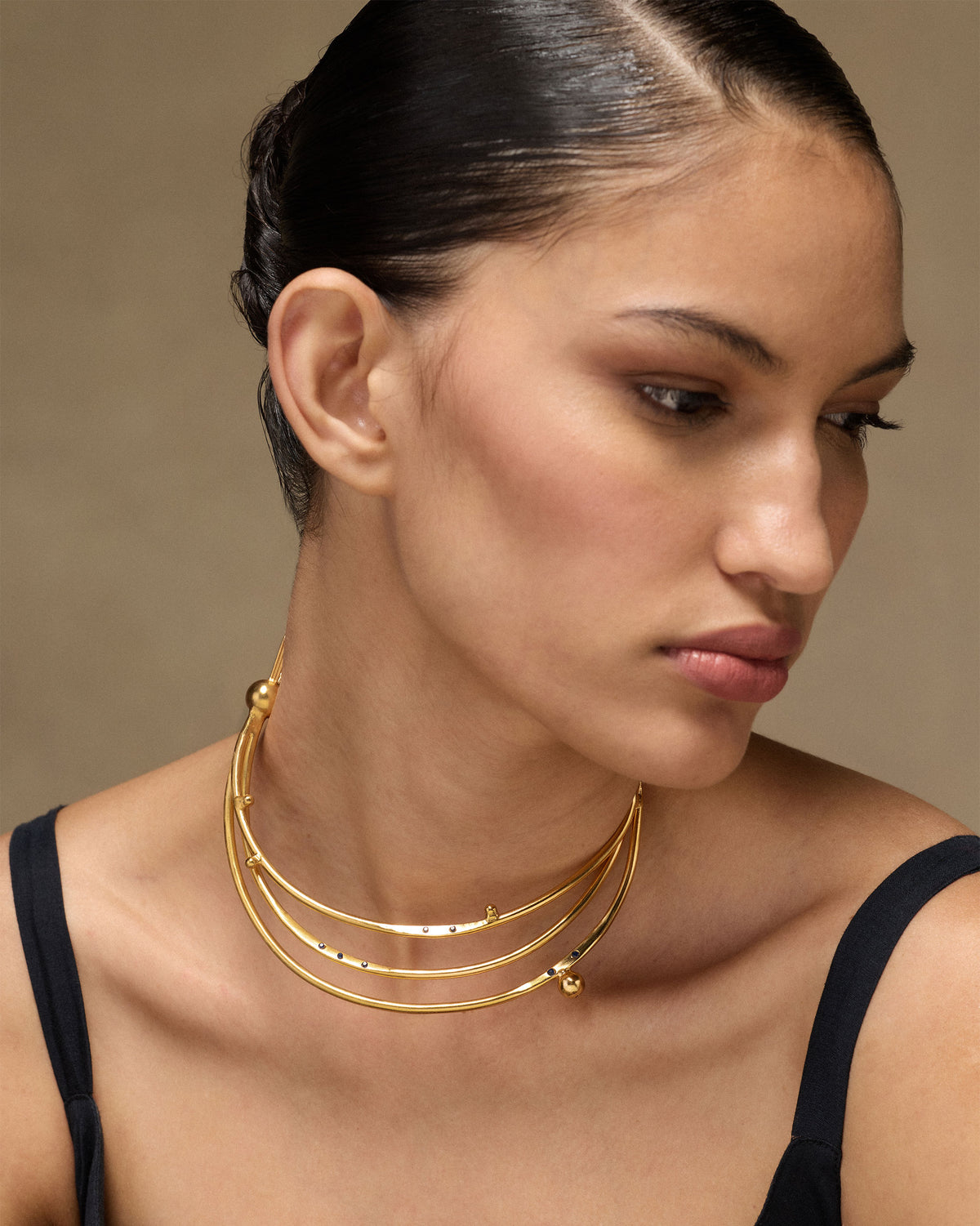 Person wearing a gold Celestial choker with three crescent tiers.