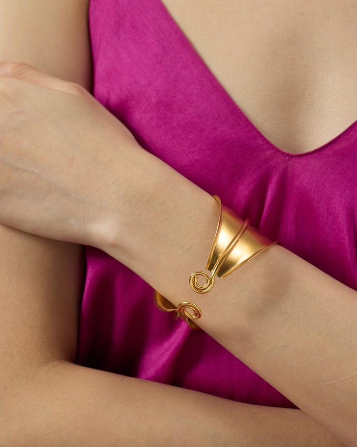 Close-up of a gold rays cuff with spiral ends on a wrist.