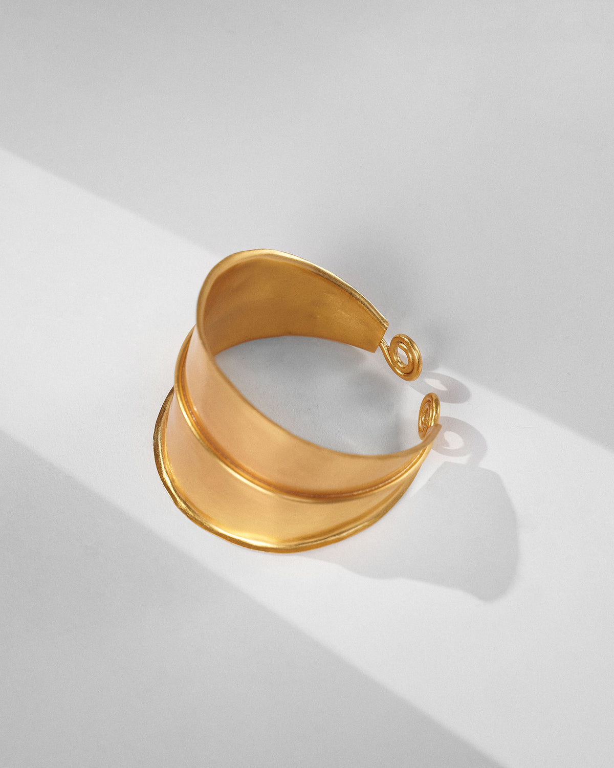 Gold rays cuff showing layered curved bands and spiral ends.
