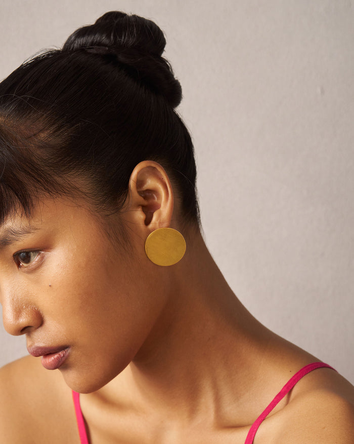 Side profile of a gold Sun Moon disc stud on a person.