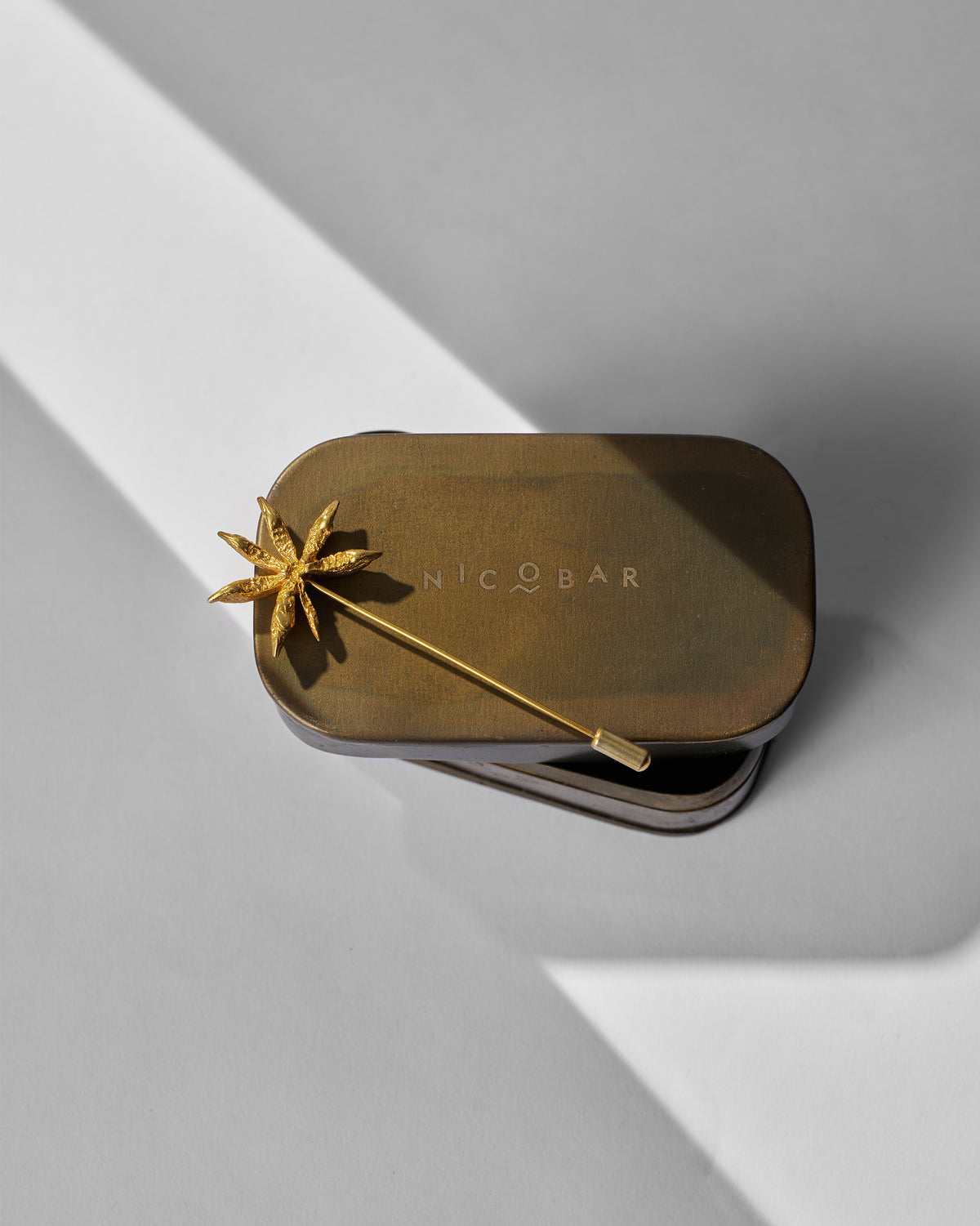 Star Anise Lapel Pin resting on a Nicobar tin.