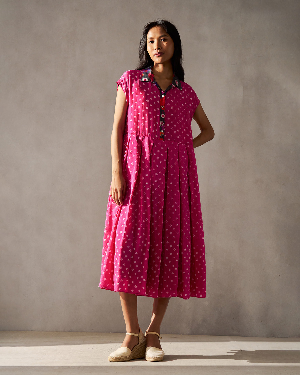 Person wearing a fuchsia bandhani Midsummer dress with a shirt collar.