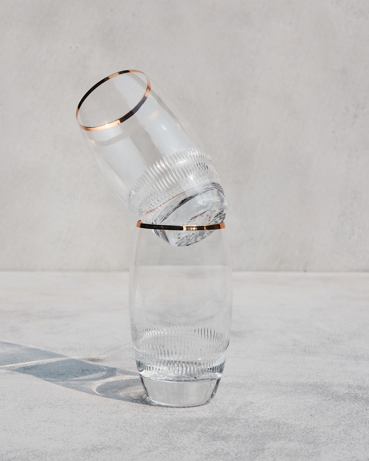 Serena highball glasses stacked to show copper rims and ribbed bases.