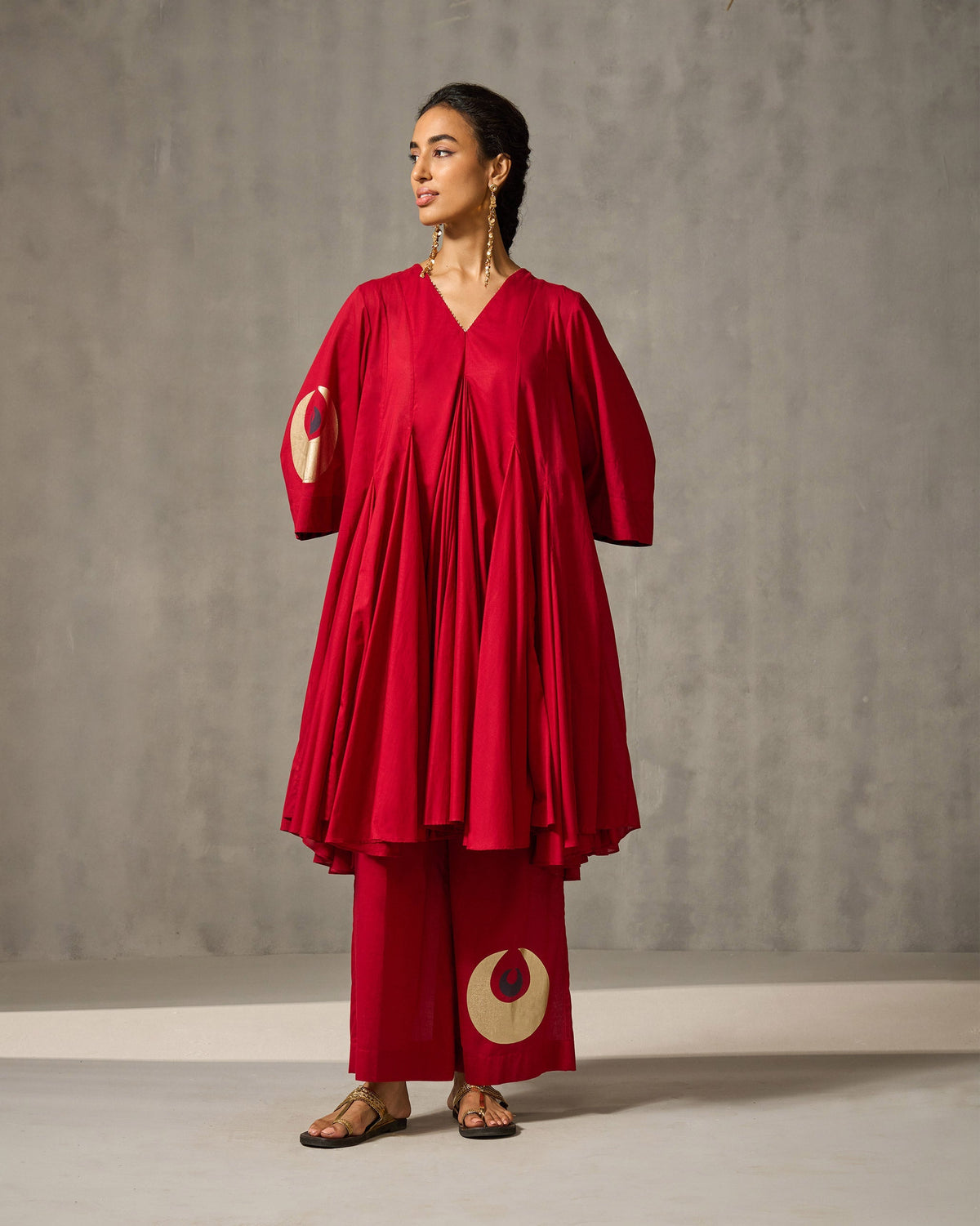 Three-quarter view of red Basic pyjamas with a gold circle motif.