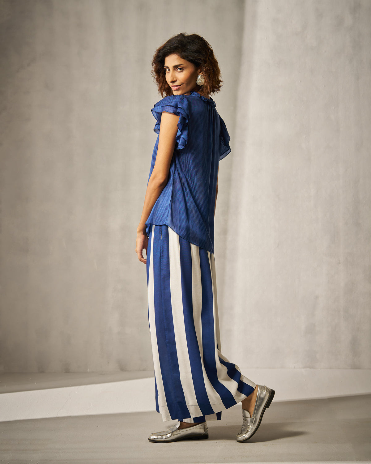 Person wearing a blue check ruffle-sleeve shirt with a relaxed fit.