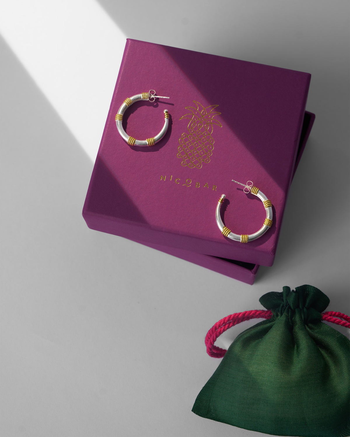 Small silver and gold dhoop chaon hoops on a purple Nicobar gift box.