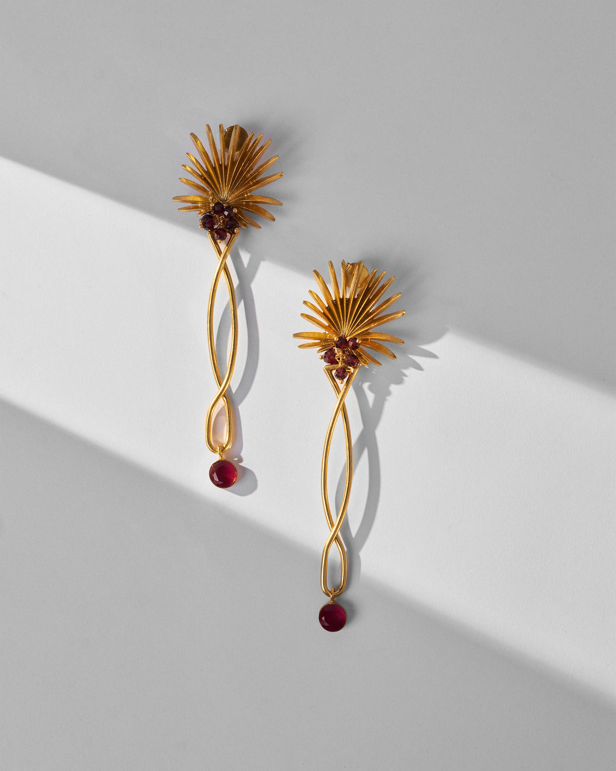 Pair of gold Palm Danglers laid flat, showing the red drops.