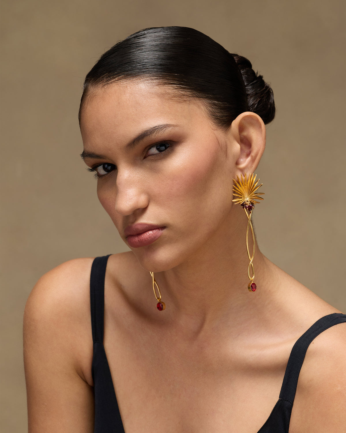 Person wearing gold Palm Danglers with long twisted drops and red beads.